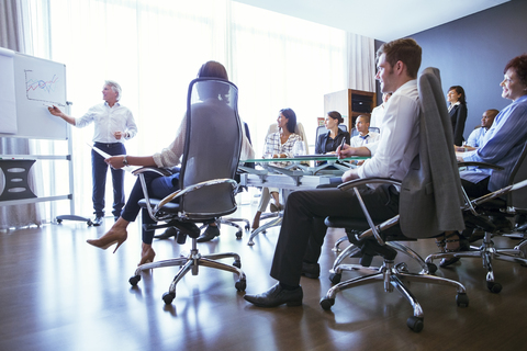 Geschäftsleute, die sich im Konferenzraum treffen und die Präsentation ihrer Kollegen verfolgen, lizenzfreies Stockfoto