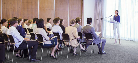 Young woman delivering speech before audience in conference room - CAIF15472