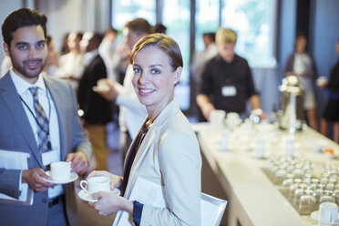 Porträt eines Mannes und einer Frau, die während der Kaffeepause in der Lobby eines Konferenzzentrums stehen - CAIF15480