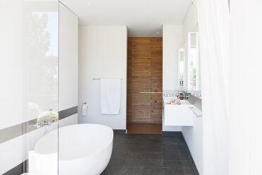 Modern bathroom interior with large bathtub and wooden door - CAIF15510