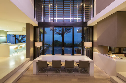 Modern dining room with fireplace and kitchen at night - CAIF15523