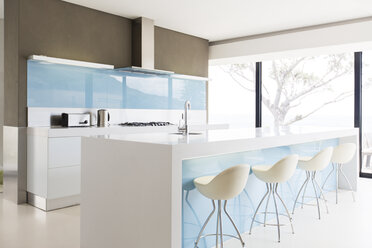 White and clean modern kitchen with stools at kitchen island - CAIF15531