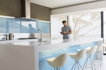 Mann benutzt digitales Tablet in moderner Küche - CAIF15536