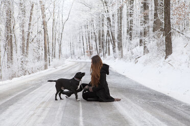 Seitenansicht einer Frau mit Hund auf der Straße im Winter - CAVF06977