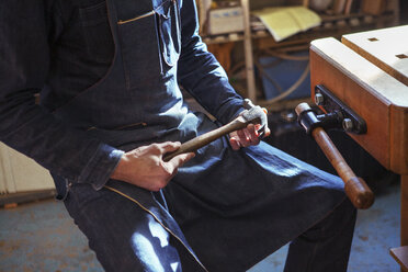 Mittelteil eines Zimmermanns, der einen Hammer in der Werkstatt hält - CAVF06996