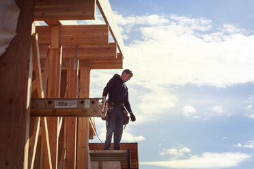 Arbeiter auf einem Holzrahmen stehend gegen den Himmel an einem sonnigen Tag - CAVF07015