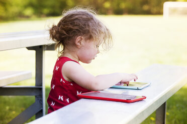 Hohe Winkel Ansicht des Mädchens mit Tablet-Computer beim Sitzen auf der Bank im Park - CAVF07054