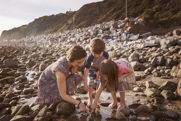 Happy family dipping finger in water at beach - CAVF07115