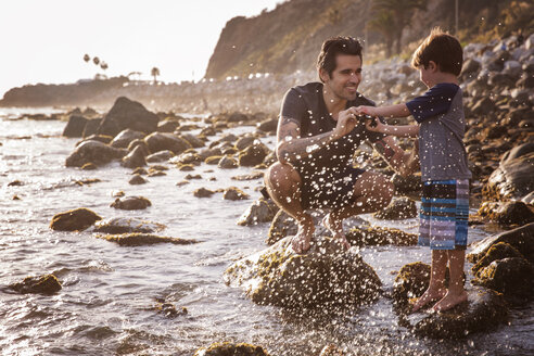 Glücklicher Vater und Sohn genießen am Strand bei Sonnenuntergang - CAVF07125