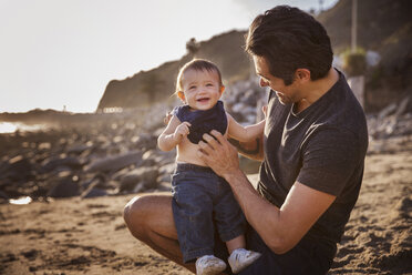 Vater mit fröhlichem kleinen Jungen am Strand - CAVF07134