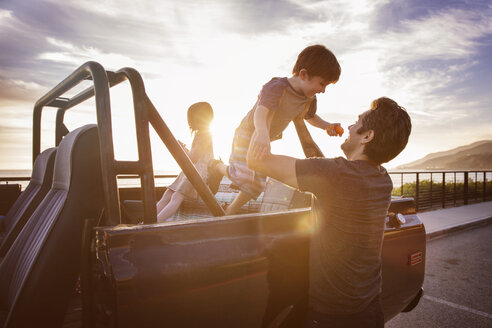 Mann hebt Junge bei Sonnenuntergang aus Pick-up-Truck - CAVF07146