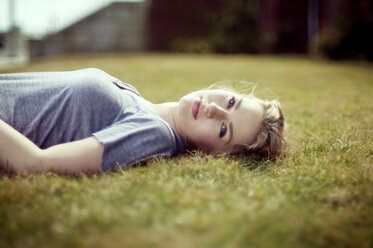 Portrait of woman lying on grassy field - CAVF07161