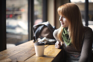 Woman looking down while sitting in cafe - CAVF07194