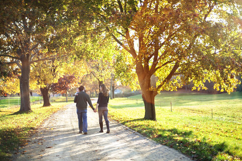 Rückansicht eines Paares mit Sohn beim Spaziergang im Park - CAVF07230