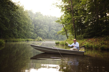 Man casting fishing rod while fishing in lake - CAVF07328