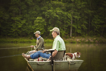 Side view of friends fishing in lake stock photo