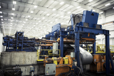 Aufrollen von Blechen auf Maschinen in einer Fabrik vor einer beleuchteten Decke - CAVF07398