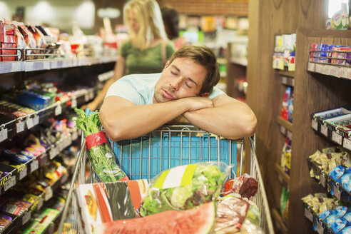 Mann schläft auf Einkaufswagen im Lebensmittelgeschäft - CAIF15552
