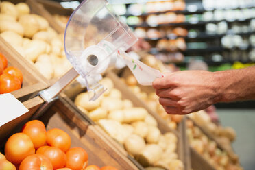 Close up of man taking plastic bag in produce section of grocery store - CAIF15572