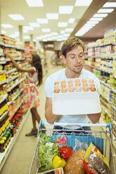 Mann untersucht Karton mit Eiern in einem Lebensmittelladen - CAIF15590
