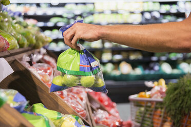 Man holding bag of produce in grocery store - CAIF15604