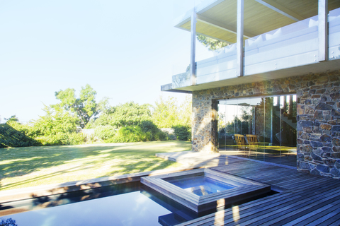 Modernes Haus mit Blick auf Pool und Holzterrasse, lizenzfreies Stockfoto