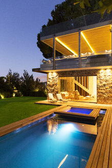 Modernes Haus mit Blick auf den beleuchteten Swimmingpool bei Nacht - CAIF15642
