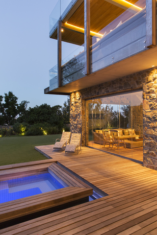 Modernes Haus mit Blick auf Schwimmbad und Holzterrasse, lizenzfreies Stockfoto