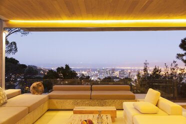 Modern living room overlooking illuminated cityscape at night - CAIF15648