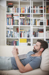 Man listening to music on sofa - CAIF15649