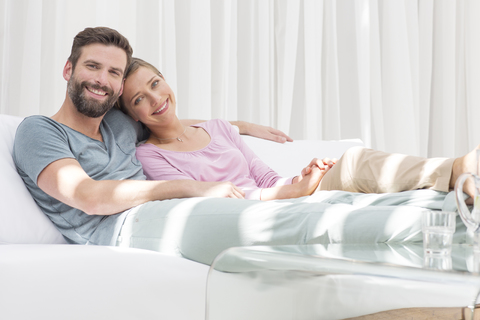 Paar entspannt zusammen auf Sofa in modernem Wohnzimmer, lizenzfreies Stockfoto