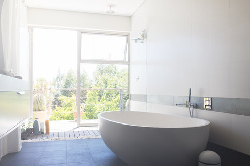 Modernes Badezimmer mit großer weißer Badewanne und Terrassentür - CAIF15682