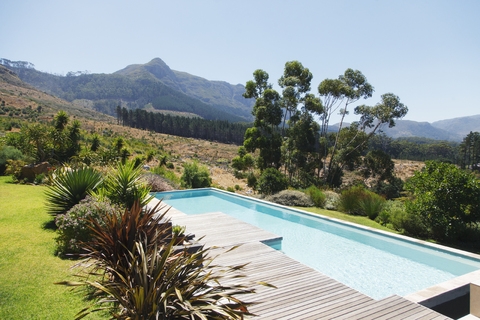 Holzterrasse und Swimmingpool in hügeliger Landschaft, lizenzfreies Stockfoto