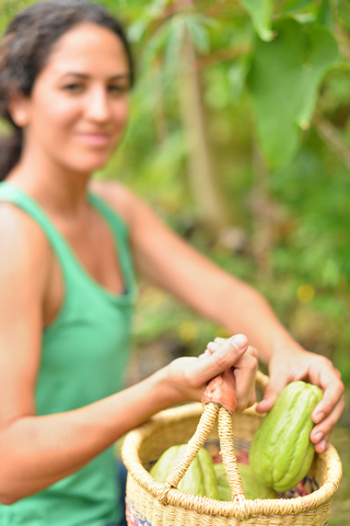 Junge Frau trägt Korb mit frischem Gemüse, lizenzfreies Stockfoto