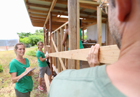Menschen bauen gemeinsam ein Holzhaus - CAIF15698