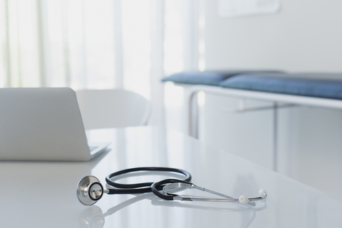 Stethoscope and laptop on white desk in doctors office stock photo