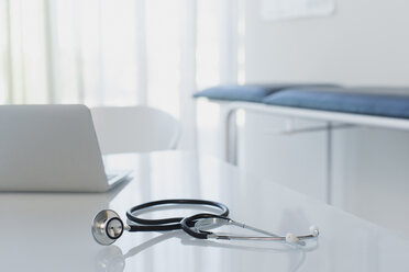 Stethoskop und Laptop auf weißem Schreibtisch in Arztpraxis - CAIF15734