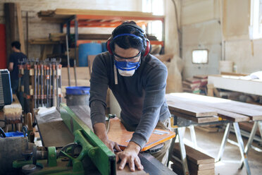 Carpenter cutting wooden plank at workshop - CAVF07451
