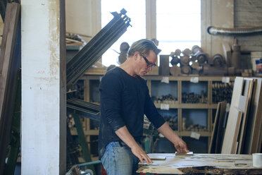 Side view of male carpenter working in workshop - CAVF07465