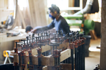 Seitenansicht eines männlichen Tischlers in einer Werkstatt mit Maschinen im Vordergrund - CAVF07468