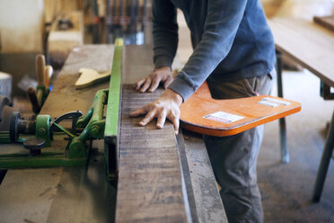 Mittelteil eines männlichen Zimmermanns, der in der Werkstatt ein Holzbrett zuschneidet - CAVF07488