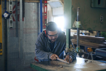 Male carpenter using machinery while working at workshop - CAVF07494