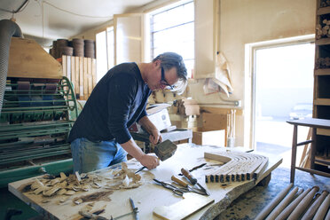 Male carpenter chiseling wood in workshop - CAVF07498