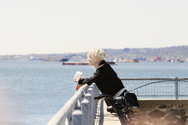 Woman leaning on railing at observation point by river against clear sky - CAVF07508