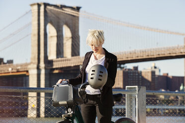 Frau steht mit Fahrrad vor der Brooklyn Bridge in der Stadt - CAVF07525