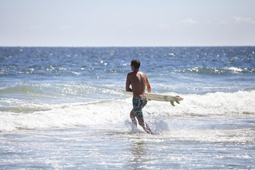 Mann mit Surfbrett im Meer gegen den Himmel - CAVF07614