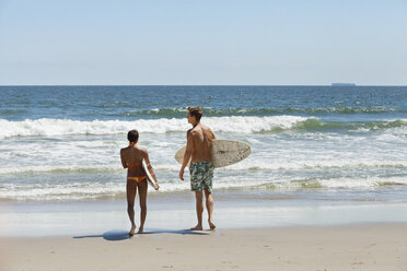 Rear view of couple carrying surfboard at beach - CAVF07643