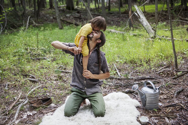 Happy father carrying daughter in forest - CAVF07716