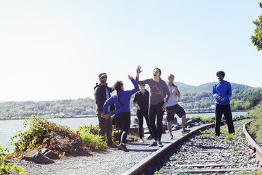 Glückliche Freunde stehen an der Bahnstrecke gegen den klaren Himmel an einem sonnigen Tag - CAVF07744