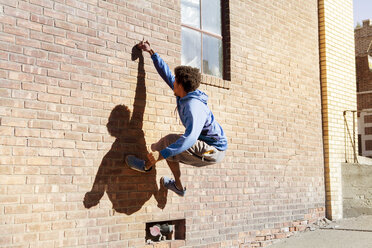Mann klettert auf Ziegelmauer - CAVF07755